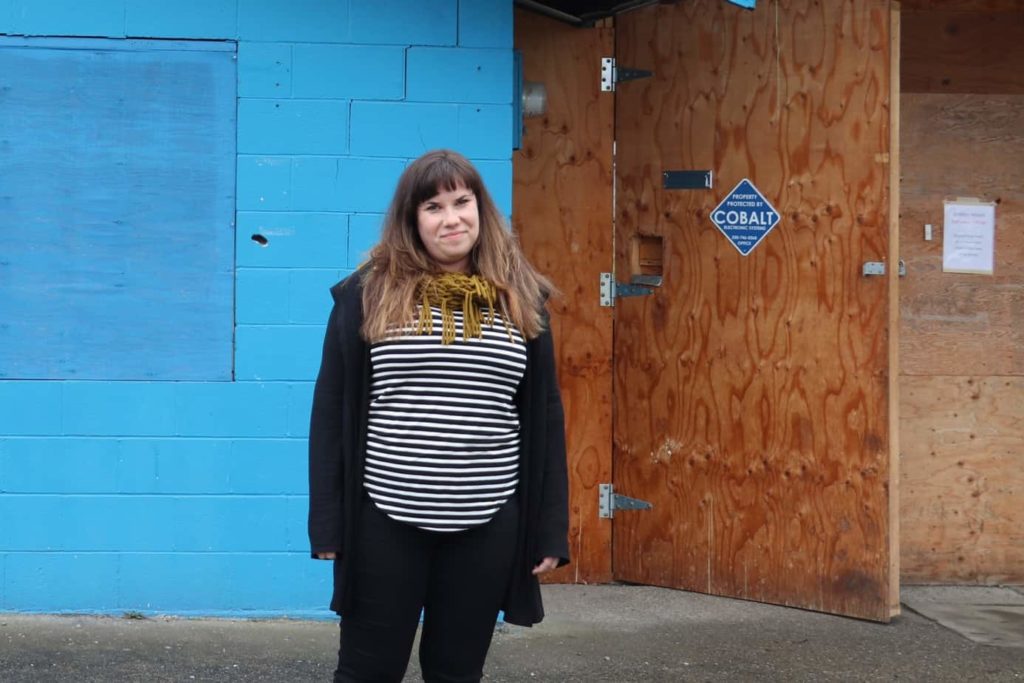 Woman stands outside building.