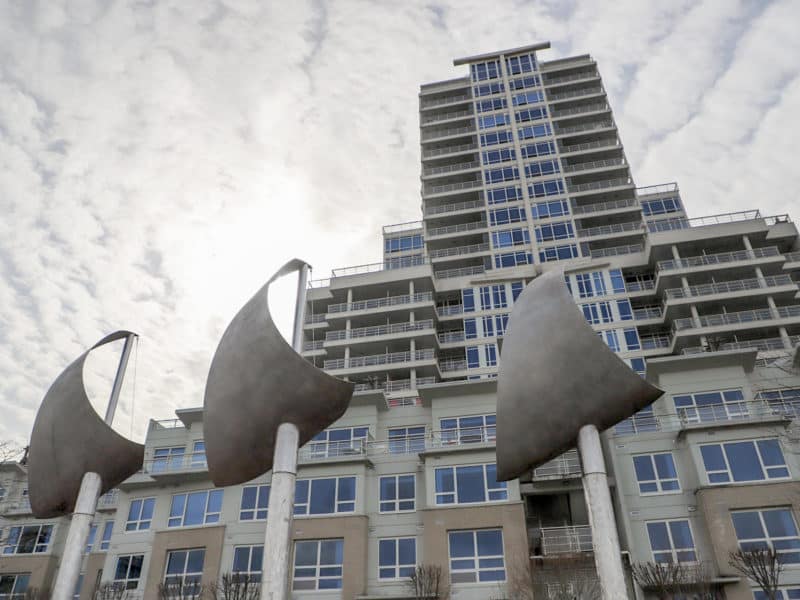 a photo of a sail statute is in the foreground of a high rise condo.