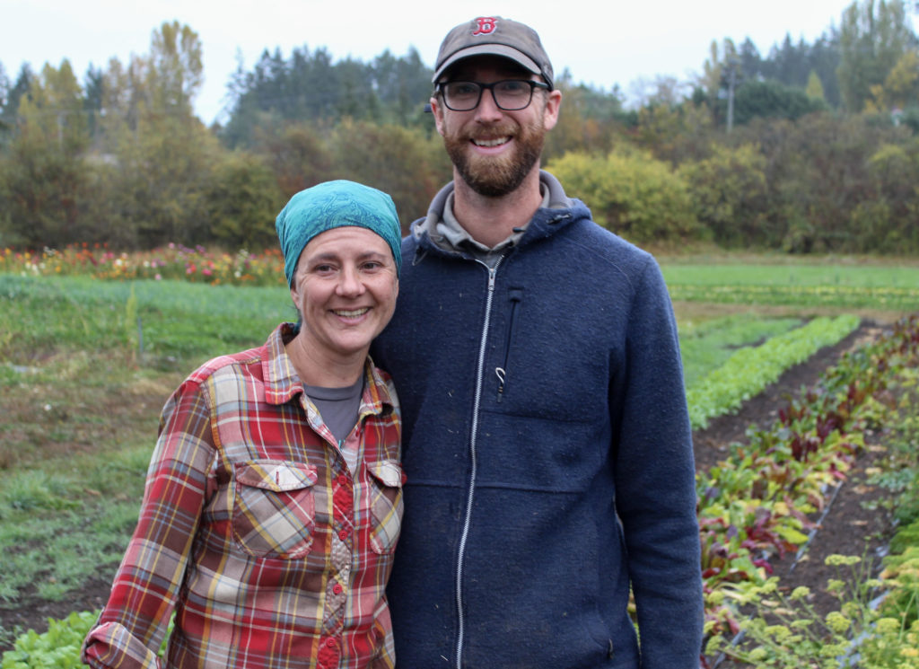 Farmers Niki Strutynski and Nick Neisingh stand in front of a planted field.