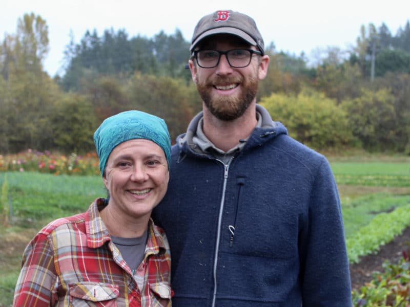 Farmers Niki Strutynski and Nick Neisingh stand in front of a planted field.