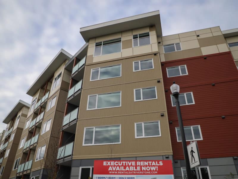 A new building with five floors stands with a sign in front showing "executive" rentals are available.
