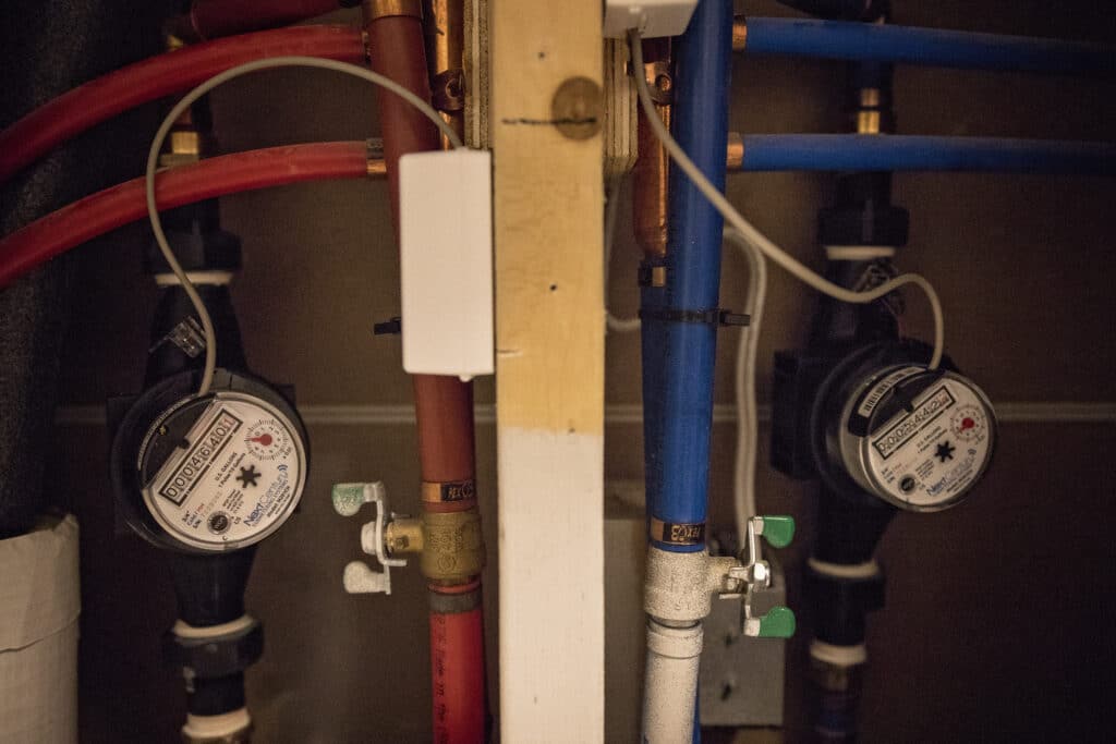Two smal dial meters connected on either side of water lines, one hot one cold.