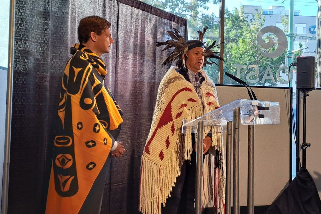 Snuneymuxw First Nation Chief Mike Wyse and Premier David Eby spoke with press while wearing traditional regalia and a gifted blanket.