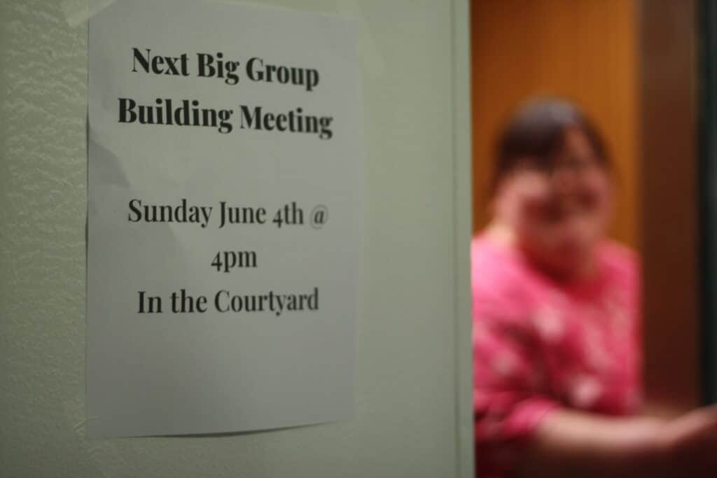 A sign reads "Next Big Group Building Meeting June 4 in the courtyard"
